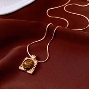 Vista macro del pendente occhio di tigre placcato oro 18K con trama martellata e catena snake