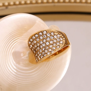 Détail macro d'une bague large concave dorée avec cristaux scintillants en pavé