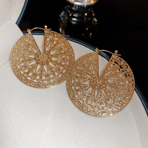 Macro shot of gold-finished circular earrings with intricate hollow geometric pattern
