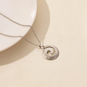 Detailed view of silver stainless steel spiral pendant with radial texture on fine chain