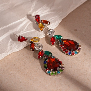 Macro detail of royal teardrop crystal earrings with multicolor gemstones and red drop