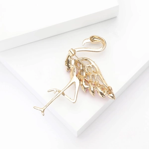 Back view of a gold flamingo brooch with rhinestone details on a white background