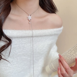 Close-up of elegant silver necklace with pink flower pendant and dangling pearl on model