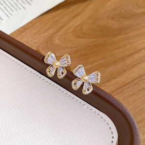 Close-up of gold-plated butterfly stud earrings with pearls and zircons on leather