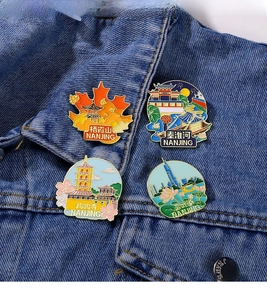 Detail of four Nanjing landmark enamel pins on denim jacket showing local architecture
