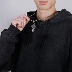 Detail of silver spider web gothic necklace pendant worn by a model on grey background
