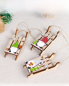 Close-up of three DIY wooden Christmas sled pendants with gnome motifs on woven fabric