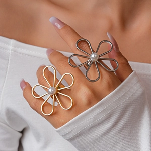 Detail of oversized hollow flower rings with pearls in gold and silver finish