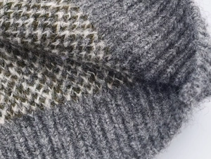 Macro view of gray and dark green geometric jacquard knit fabric with brushed texture