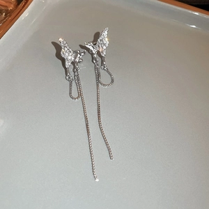 Détail de boucles d'oreilles papillon argentées avec pampilles et zircons étincelants