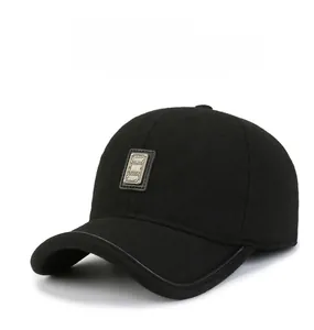 Close-up of black winter baseball cap with metal logo plate and premium leather brim edge