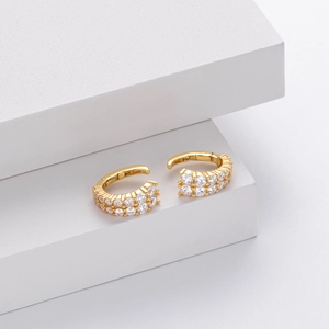 Detailed macro view of gold hoop earrings with double-row white zircon inlay on stone
