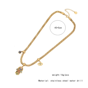 Detail showing the Hamsa hand and evil eye pendant on a gold stainless steel chain