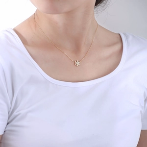 Close-up of sparkling 925 sterling silver snowflake necklace with gold finish on a model
