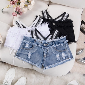 Dettaglio flat lay di pantaloncini di jeans strappati blu, bianchi e neri su divano in pelle