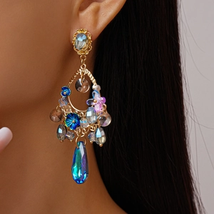 Detailed close-up of retro gold floral earrings with blue and purple crystals on model