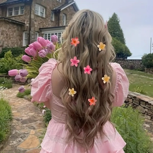 Outdoor shot of various candy-colored plumeria flower hair clips on long wavy hair