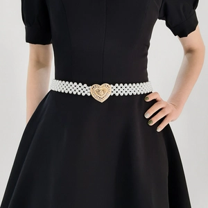 Detailed view of elastic pearl belt featuring a golden heart-shaped metal buckle on a dress