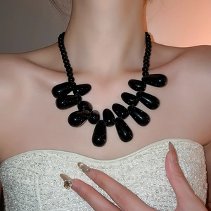 Détail macro du collier à pendentifs gouttes en acrylique noir sur mannequin