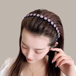 Detailed view of an elegant black floral headband with pink rhinestones on a female model