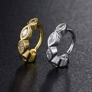 Close-up of gold and silver hinged belly rings featuring marquise-cut clear gemstones