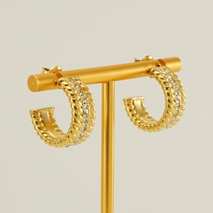 Golden C-shaped stainless steel twisted hoop earrings with crystal inlay on T-stand