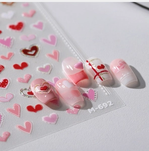 Detailed view of M-692 heart nail stickers with pink 3D patterns and gold accents