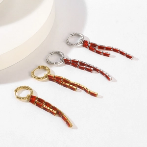 Detailed macro of 18K gold and silver long tassel earrings with red zircon stones