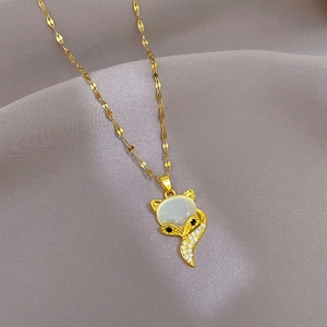 Macro shot of gold fox pendant with white cat-eye stone and crystal accents
