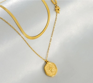 Close-up of golden double-layer necklace with star pendant and snake chain detail