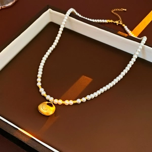 Macro detail of a vintage pearl necklace with a matte gold fortune bag pendant in a box