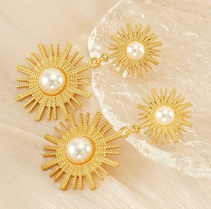 Détail de boucles d'oreilles soleil vintage dorées avec perles sur fond de soie