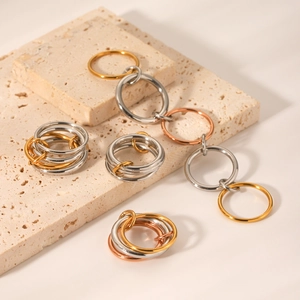 Detailed view of stacked gold, silver and rose gold polished stainless steel rings on stone