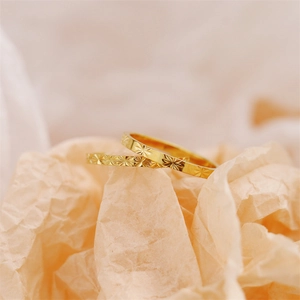 Detail of two 18K gold plated titanium steel rings with starburst texture on paper