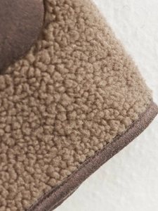 Detailed macro view of the brown Sherpa fleece fabric texture with dark brown piping edge