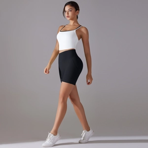 Side view of white cross-back sports bra with black trim and high-waisted black biker shorts