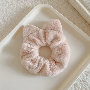 Close-up of plush cat ear scrunchie in light pink with soft faux fur texture