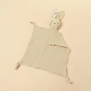 Detailed texture of beige cotton gauze baby comforter with bunny ears and knotted corners