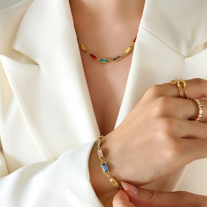 French vintage gold jewelry set with colorful zircons on a model in a white blazer