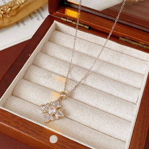 Close-up of flower pendant necklace with white zircons on beige fabric jewelry box insert