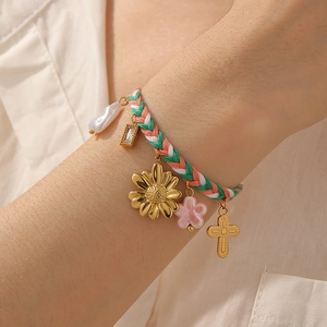Detailed shot of handmade woven charm bracelet with gold sunflower and resin flower