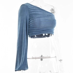 Détail du haut court bleu à une épaule montrant la texture froncée et le tissu élastique