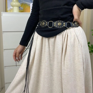 Detail of a vintage Y2K black leather belt with bronze studs and sun pattern fringe