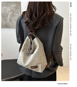 Detail of light gray matte leather backpack with brown woven strap on gray blazer