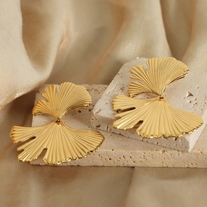Elegant golden ginkgo leaf earrings with detailed veins on a textured stone base