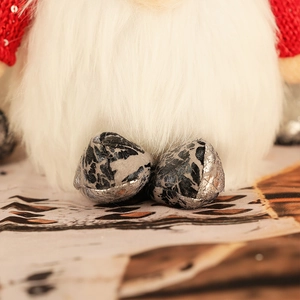 Macro detail of plush Christmas gnome showing soft white faux fur and patterned silver boots
