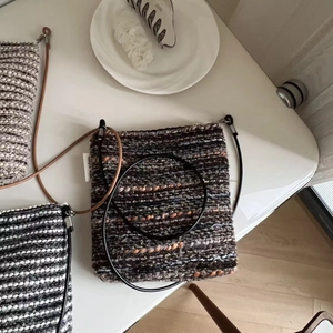 Close-up of three woven stripe crossbody bags with leather straps and logo tags