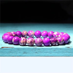 Macro detail of 8mm purple striped agate beads on a rustic blue wooden background
