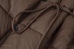 Détail de la veste matelassée marron avec boutons noirs et cordon de serrage assorti