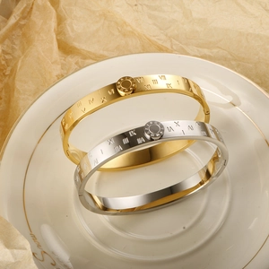 Polished titanium steel roman numeral bangles in gold and silver plating on ceramic plate